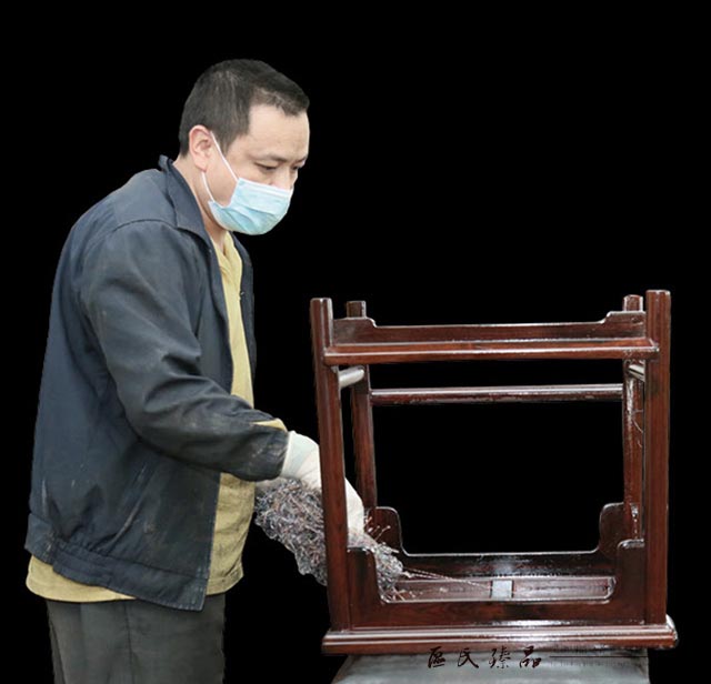 區(qū)氏臻品工匠正在對一件家具仔細上生漆。這道工序,讓紅木家具一下子有了溫潤的質感